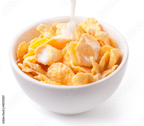 Milk pouring into a bowl of corn flake isolated on white