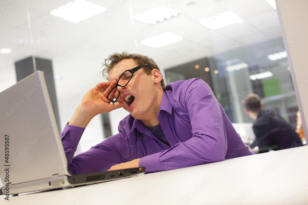 bored yawning businessman with laptop in the office bored yawning businessman with laptop in the office
