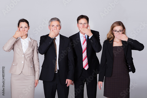 Four businesspeople gesturing for silence photo