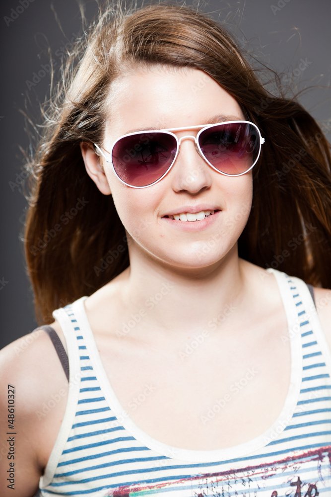 Pretty brunette teenage girl with sunglasses. Studio shot.