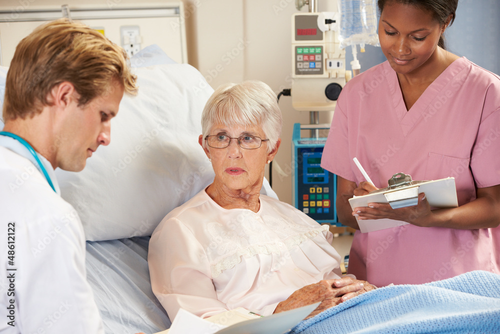 Fototapeta premium Doctor With Nurse Talking To Senior Female Patient In Bed