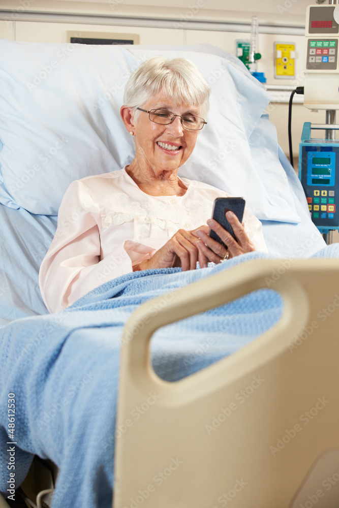 Obraz premium Senior Female Patient In Hospital Bed Using Mobile Phone
