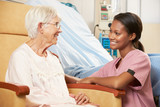 Nurse Talking To Senior Female Patient Seated In Chair
