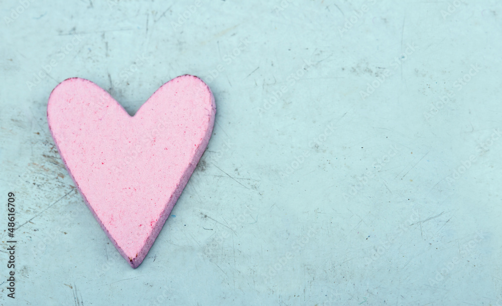 Single pink heart on light blue wooden background
