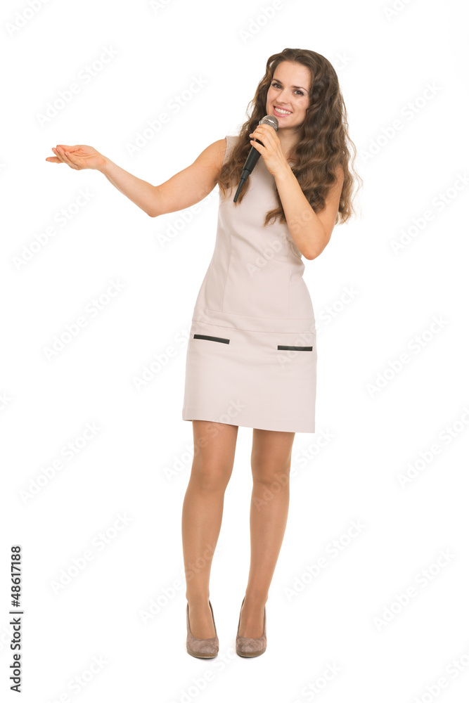 Happy young woman with microphone pointing on copy space Happy young woman with microphone pointing on copy space