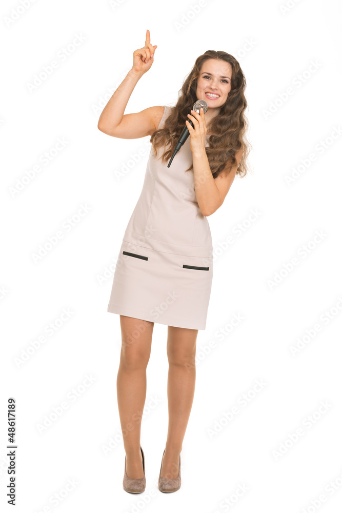 Happy young woman with microphone pointing up on copy space Happy young woman with microphone pointing up on copy space