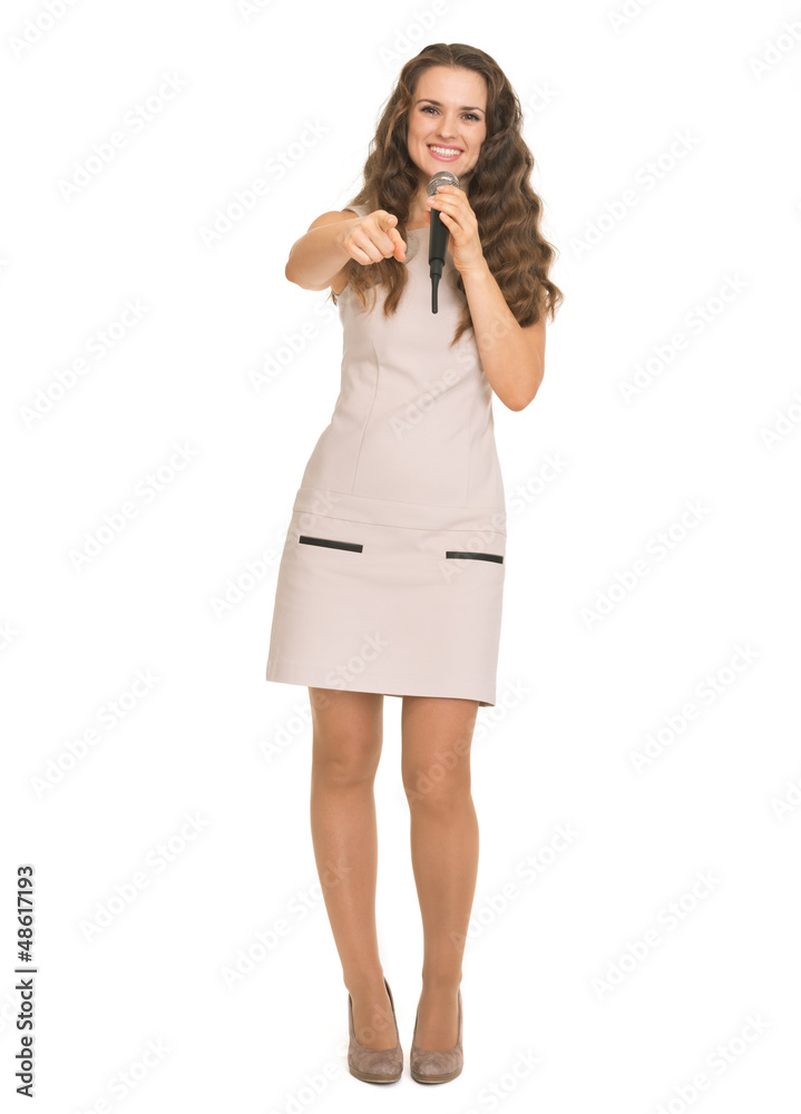 Smiling young woman with microphone pointing in camera Smiling young woman with microphone pointing in camera
