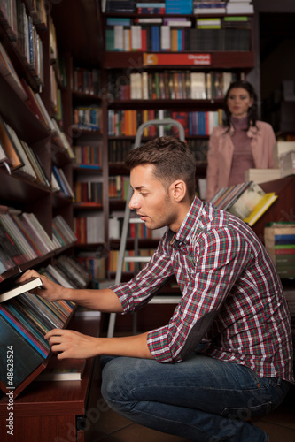 young guy taking a book from a shelf