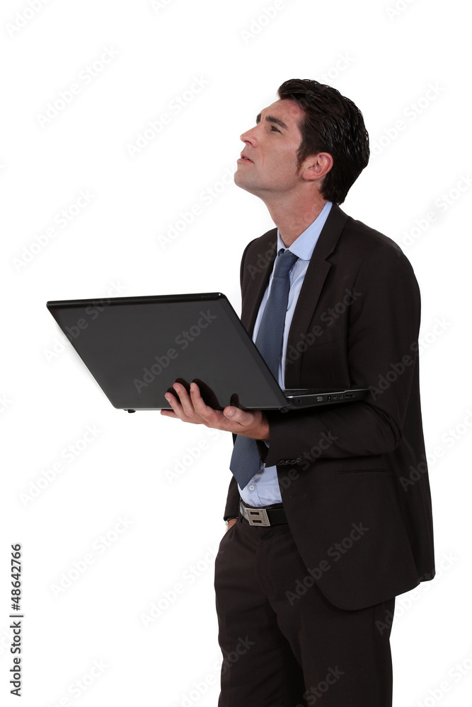 Businessman looking upwards and holding a laptop