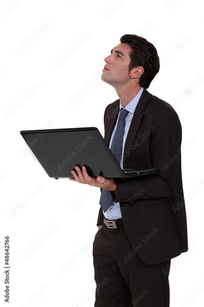 Businessman looking upwards and holding a laptop Businessman looking upwards and holding a laptop