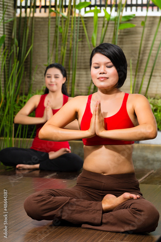 Asian women doing yoga in tropical setting
