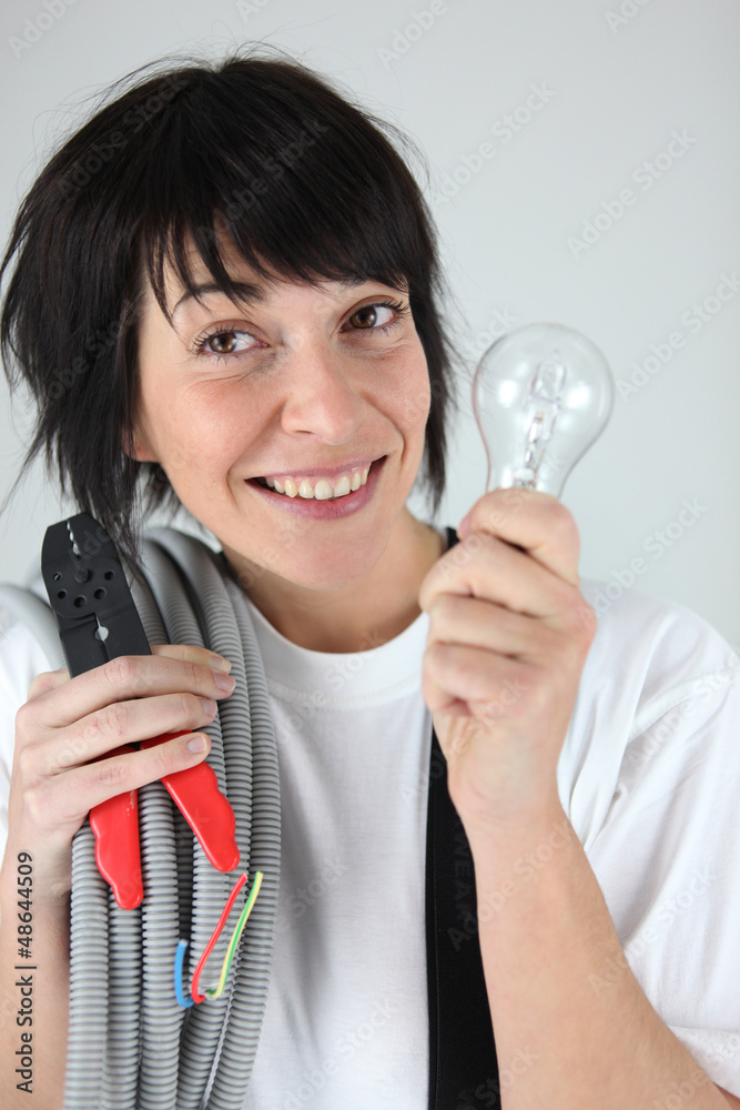 Female electrician holding replacement wiring and bulb Female electrician holding replacement wiring and bulb