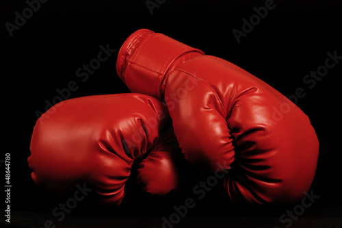 Vintage boxing gloves emerging from black background © Nodokthr