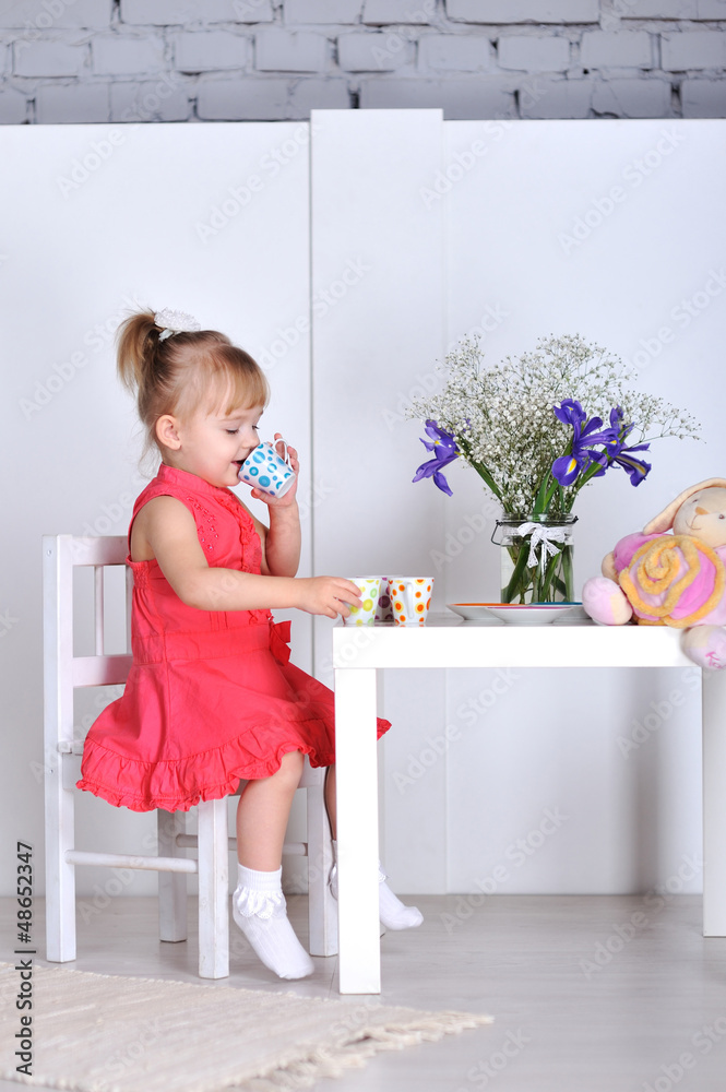 A little girl plays with dolls and dishes