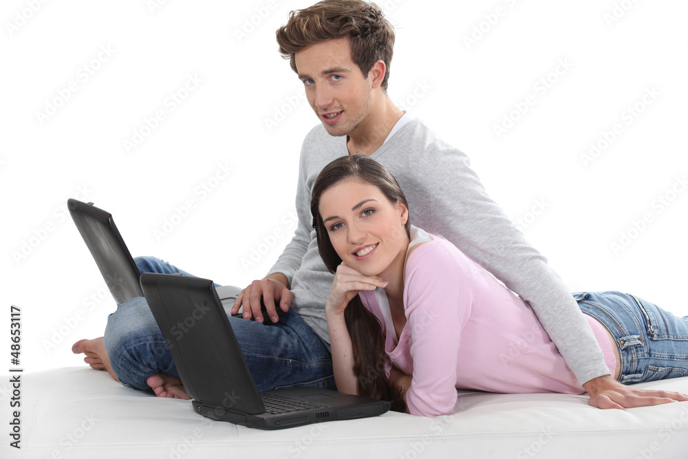 Couple laying down with two laptops Couple laying down with two laptops