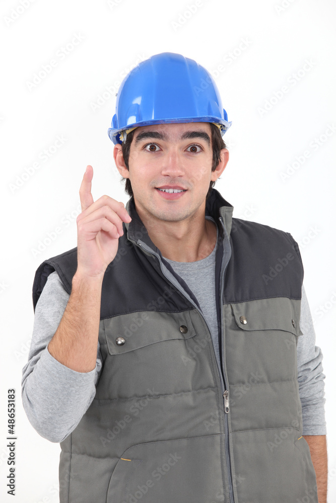 A young construction worker raising his finger. A young construction worker raising his finger.