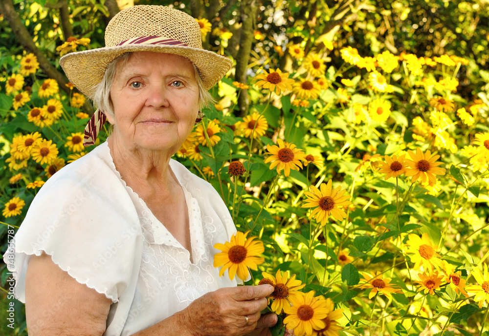Senior woman with flowers in garden.