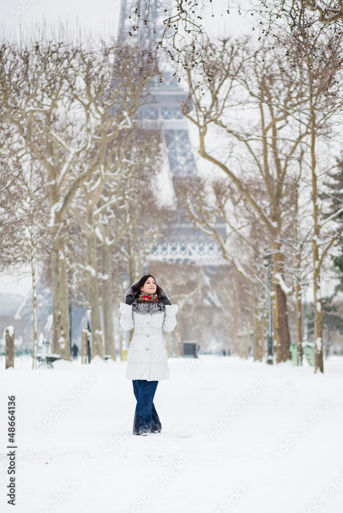Beautiful girl in fur hood walking near the Eiffel tower in Pari
