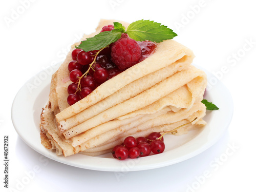 Delicious pancakes with berries and jam on plate on wooden