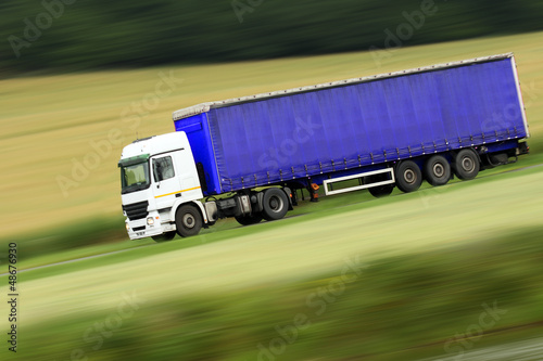 large blue truck speeding on highway photo