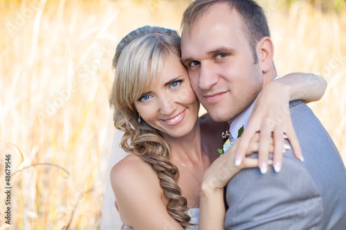 Happy young bride and groom hugging in grass in wedding day