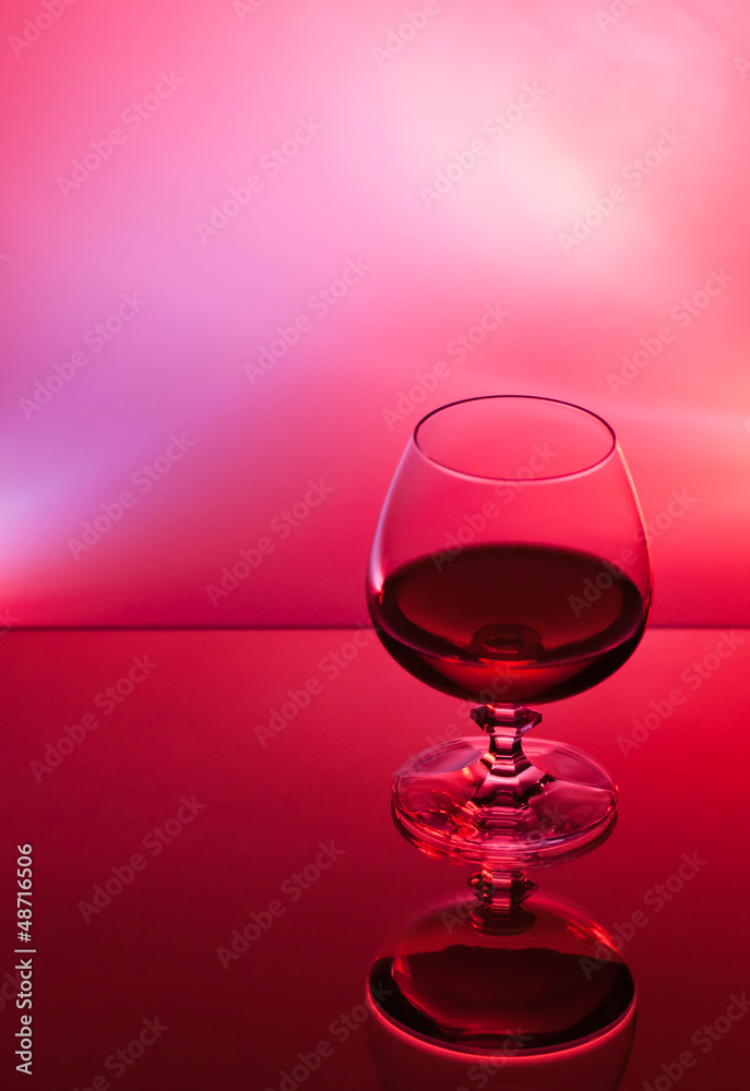 Ein Glas mit Alkohol vor rotem Hintergrund