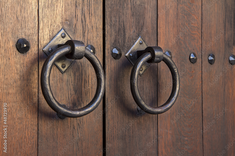 Old medieval metal handles on antique dark wooden door Old medieval metal handles on antique dark wooden door