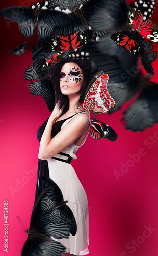 Woman with art make up in dress and red butterflies