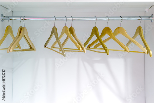 Canvas Print Yellow wooden hangers in a closet