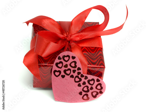 Red gift tied up by a bow and a card heart
