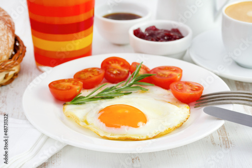 fried egg with tomato and glass of orange juice