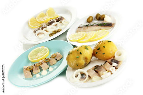 Dishes of herring on plates isolated on white