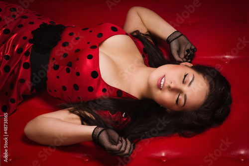 Pin-up girl lying on a red leather couch