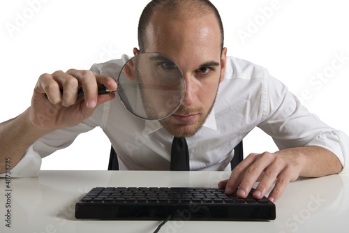 Businessman looks on the computer with a lens