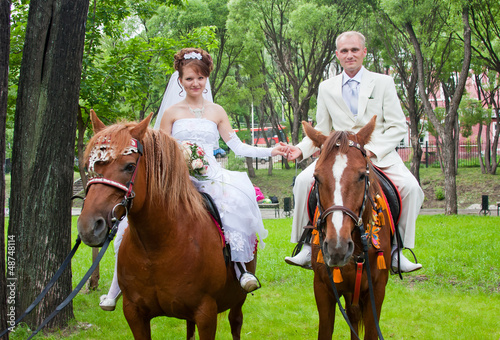 a groom and fiancee sit on two horse