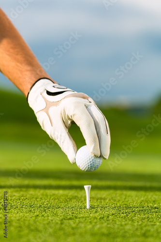 Hand hold golf ball with tee on course