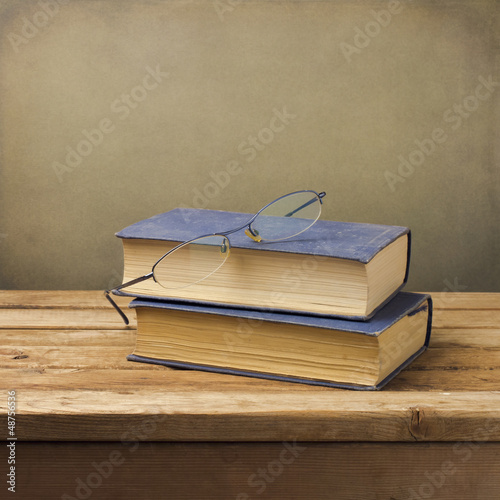 Old vintage books with glasses on wooden table
