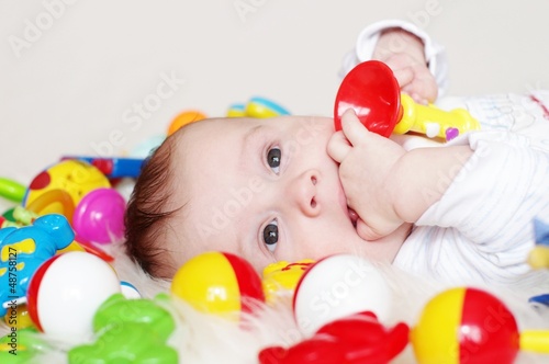 The four-months baby lies among toys