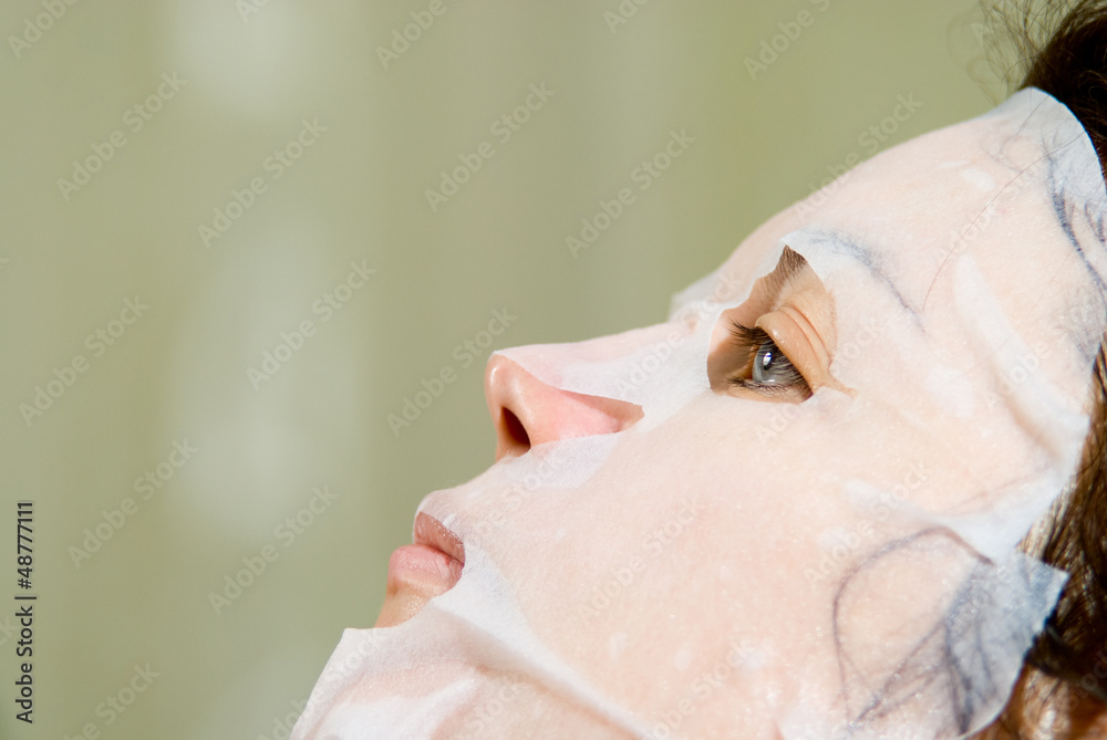 Naklejka premium Portrait in Profile woman applying rejuvenating facial mask on h