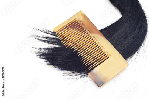 Black hair and comb on white background