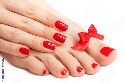 Red manicure and pedicure with a bow. isolated