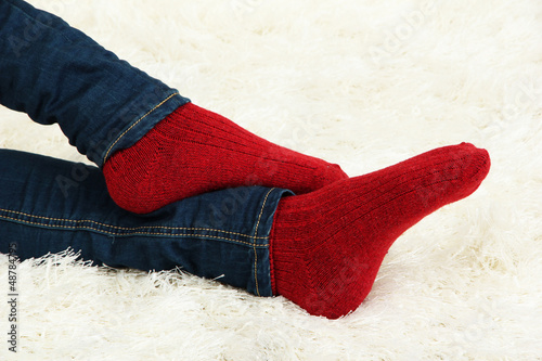 Female legs in colorful socks on white carpet background