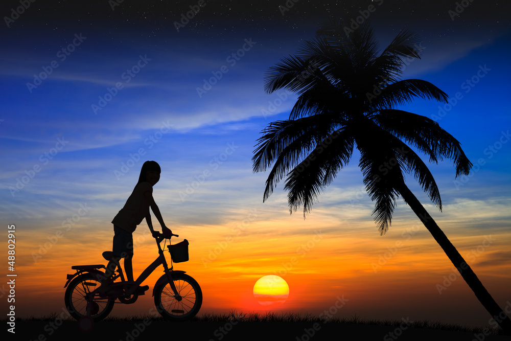 Fototapeta premium Silhouette daughter riding a bicycle on the sunset
