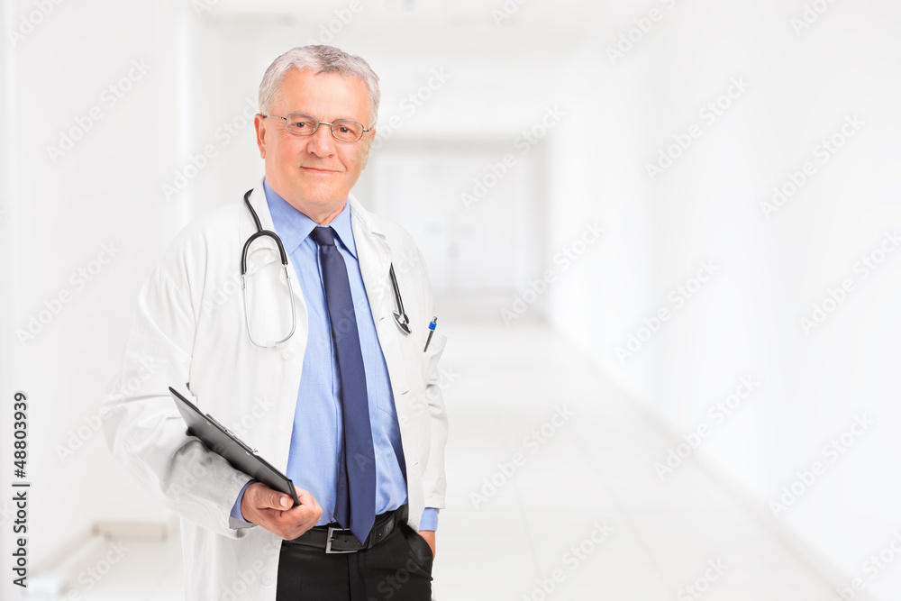Male doctor holding a clipboard and standing in a hospital Male doctor holding a clipboard and standing in a hospital