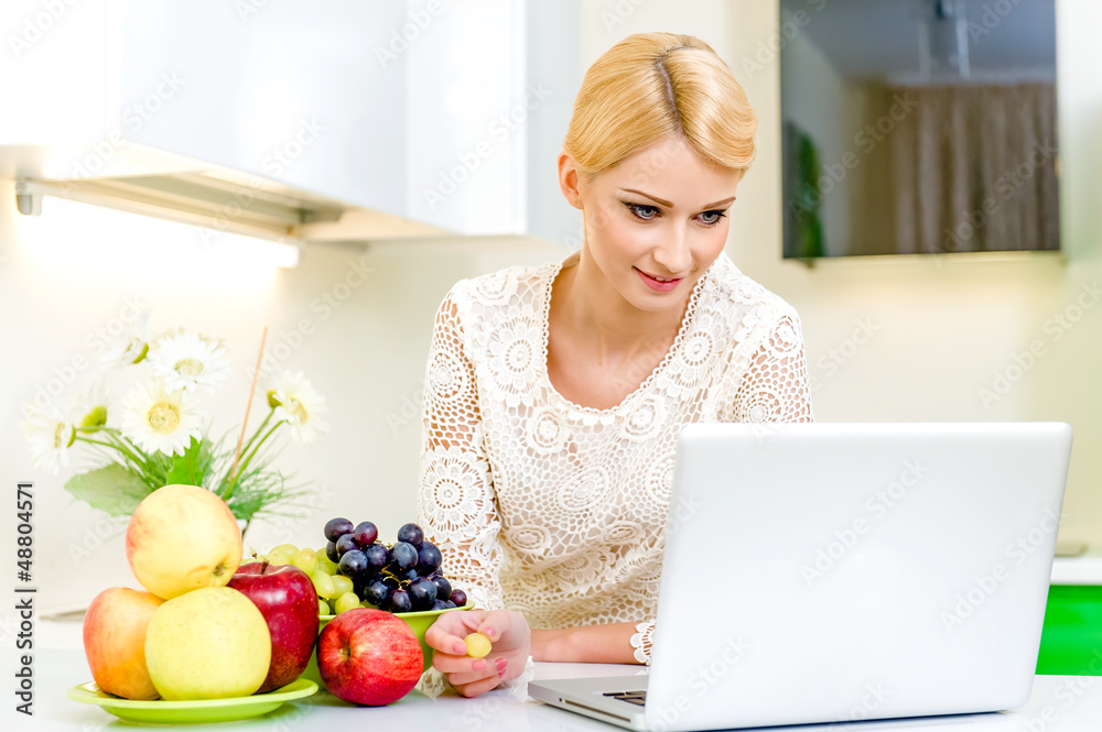 Attractive young woman with computer in the kitchen