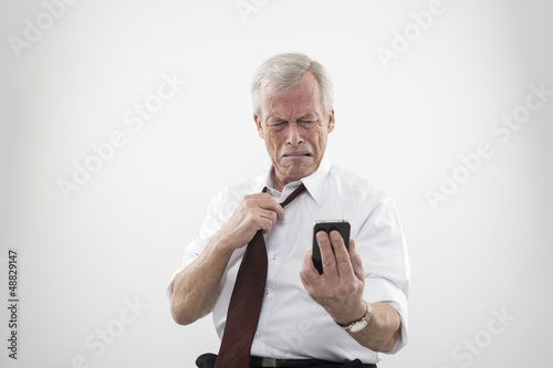 Senior man reacting in disgust to his mobile © Instudio68