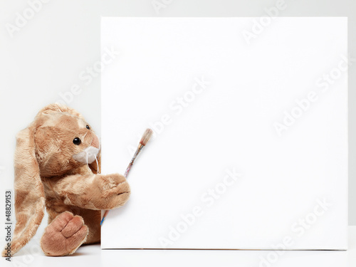 Stuffed bunny peeking behind blank board © Karin & Uwe Annas