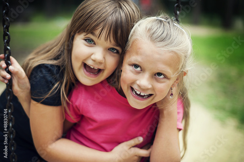 Happy little girls swinging in a park