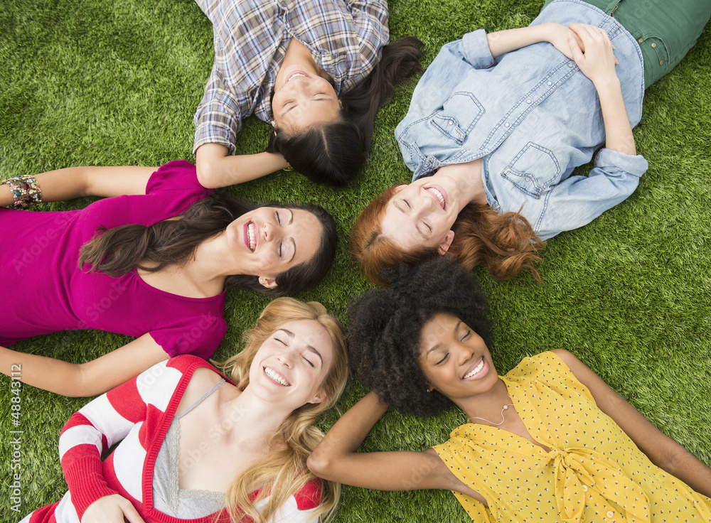 Smiling women laying in grass together Smiling women laying in grass together