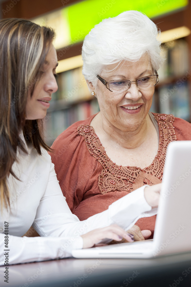 Hispanic teacher helping senior student with laptop Hispanic teacher helping senior student with laptop